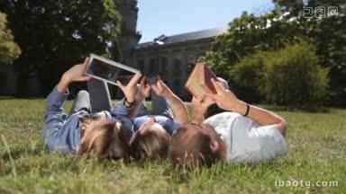 低处的三个大学生躺在绿色的草地上看书